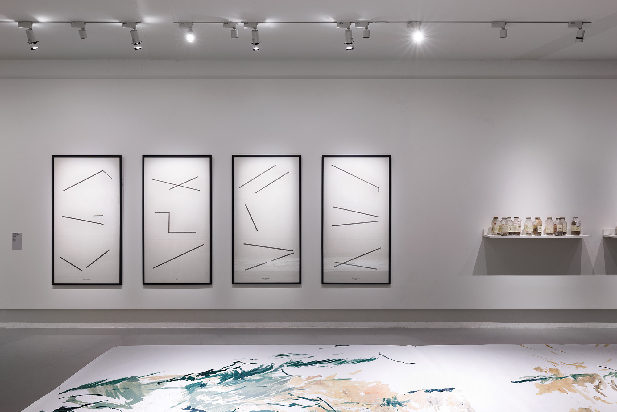 Quatre cadres avec des lignes noires sur fond blanc, et quelques objets sur une étagère.